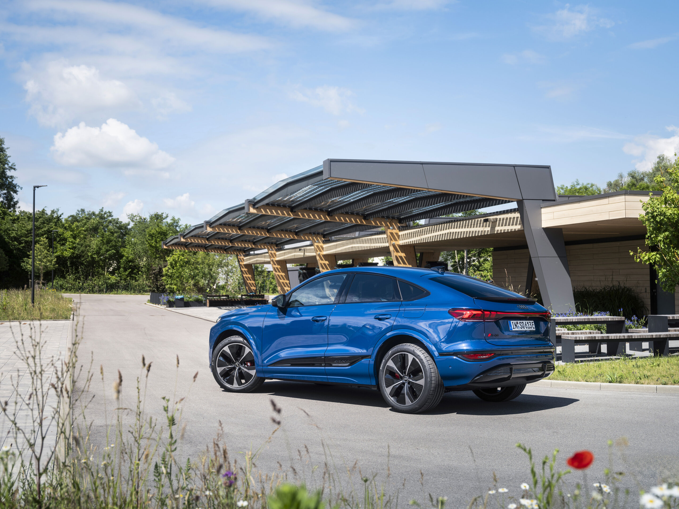 Audi SQ6 Sportback e-tron - An Audi SQ6 Sportback e-tron in Ascari blue metallic is basking in the mid-day sun in front of a fast charging station.