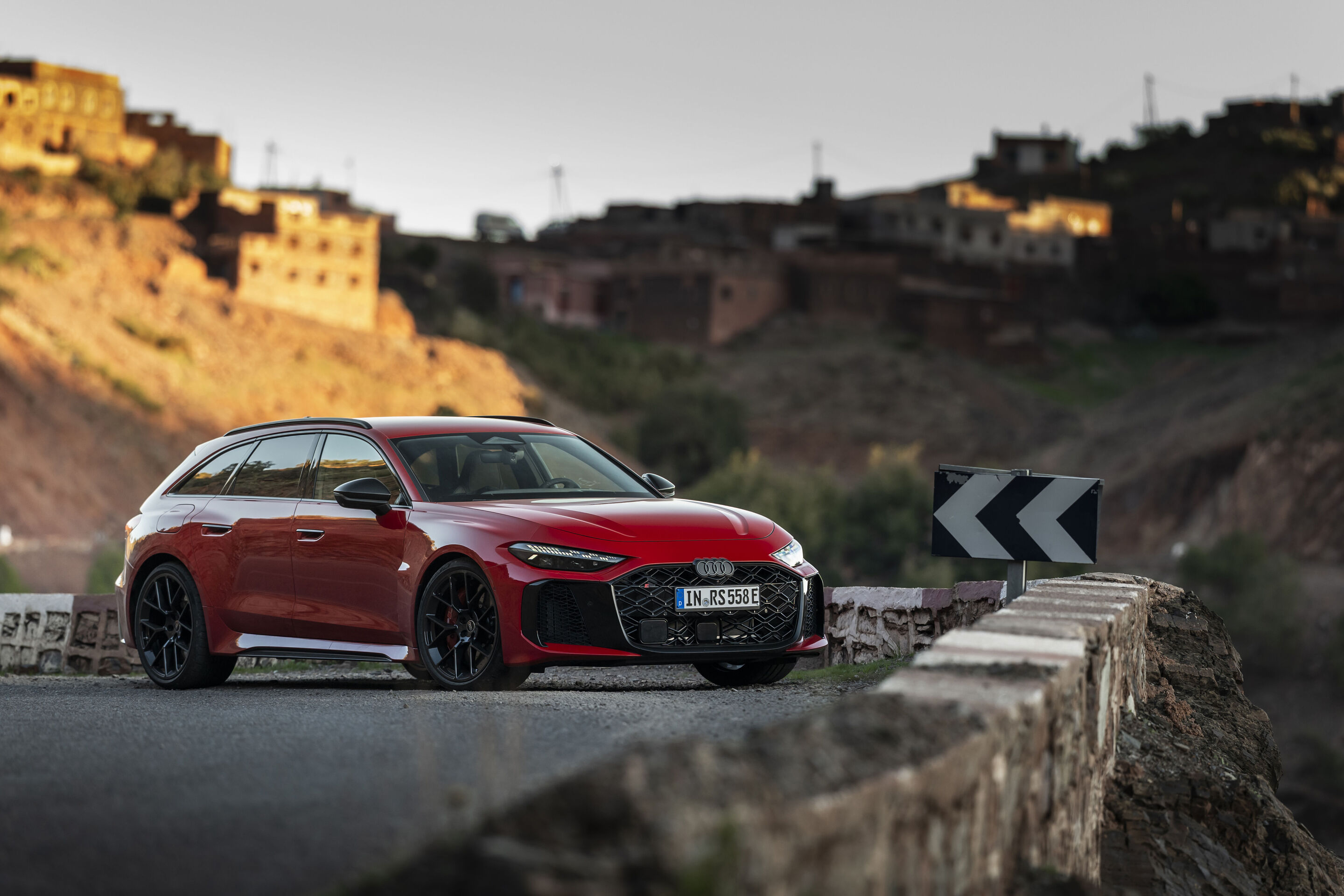 Audi RS 5 Avant - The Audi RS 5 Avant in Progressiv red on a winding mountain road near a Moroccan village – precise driving dynamics on demanding terrain.