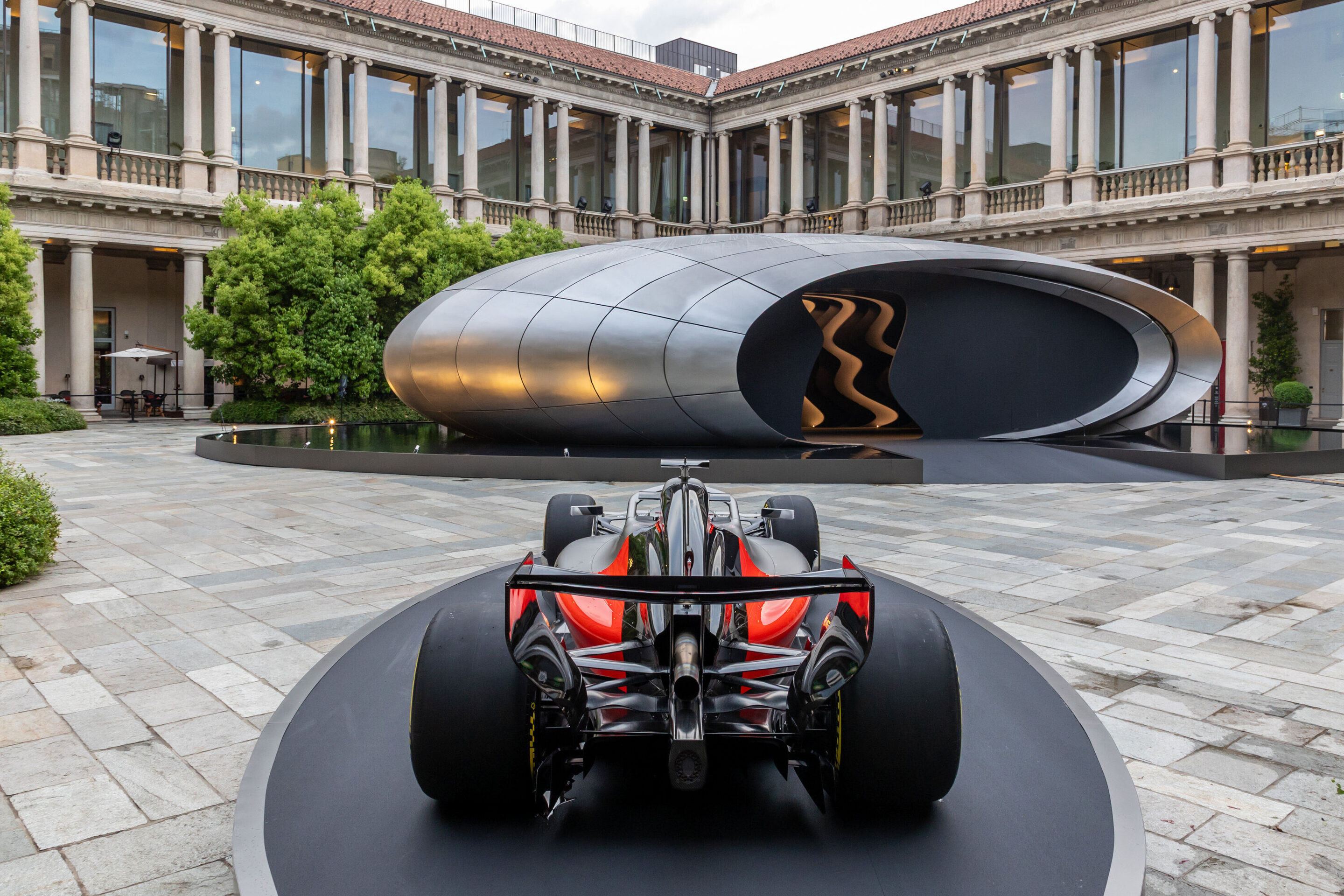 Audi at Milan Design Week 2026 - Rear view of the Audi Formula 1 show car Audi R26 displayed on a circular platform. In the background, Audi’s installation “Origin” shown at Milan Design Week 2026.